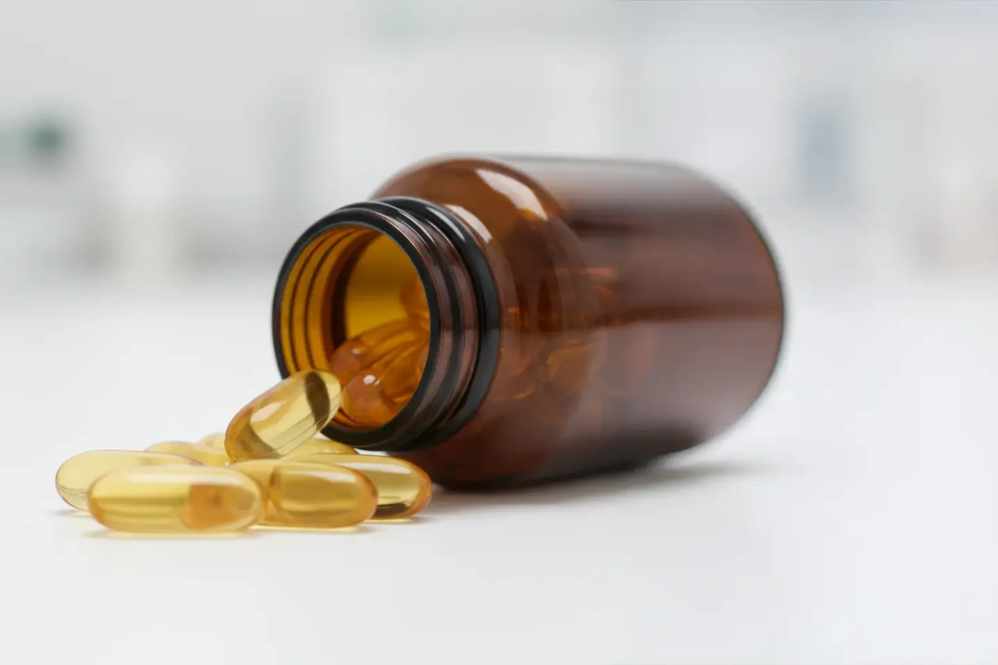 Cápsulas de aceite de pescado Omega-3 de alta pureza ricas en EPA y DHA derramadas de un bote ámbar.